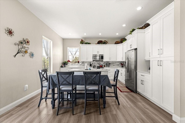 kitchen with light countertops, appliances with stainless steel finishes, a kitchen bar, and light wood finished floors