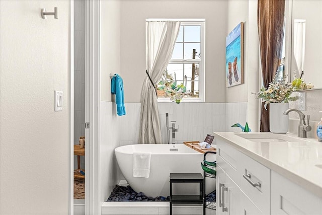 bathroom with a freestanding tub, wainscoting, and vanity