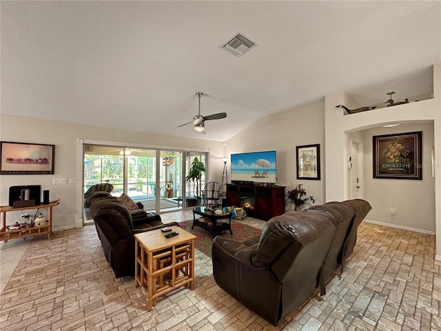 living area featuring a ceiling fan, lofted ceiling, brick floor, baseboards, and visible vents