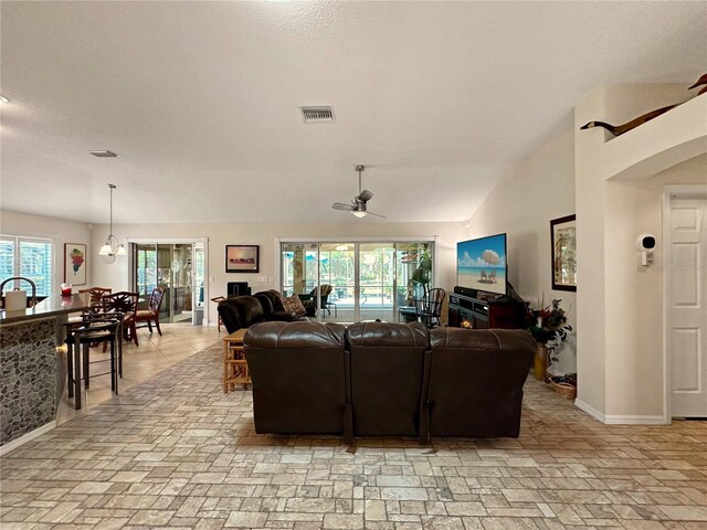 living area featuring baseboards, lofted ceiling, ceiling fan, and visible vents