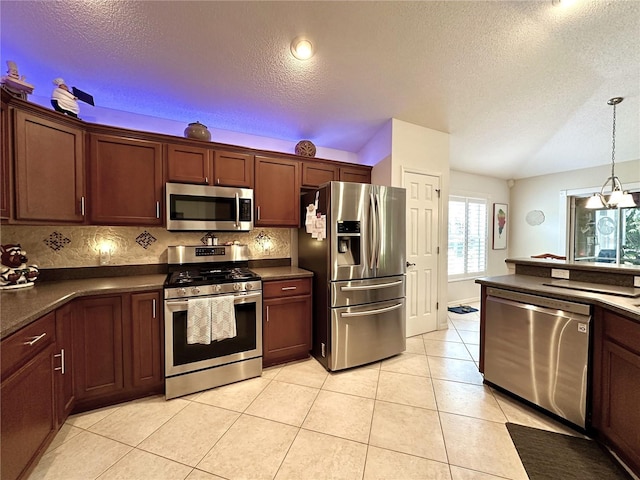 kitchen featuring tasteful backsplash, decorative light fixtures, light tile patterned floors, dark countertops, and appliances with stainless steel finishes