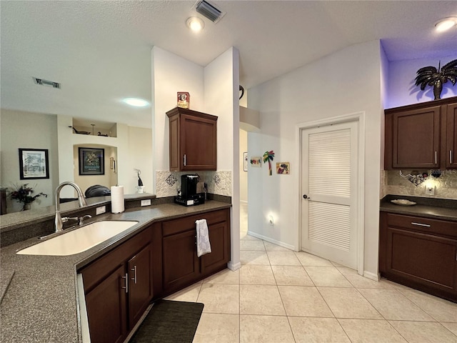 kitchen with a sink, dark countertops, and visible vents