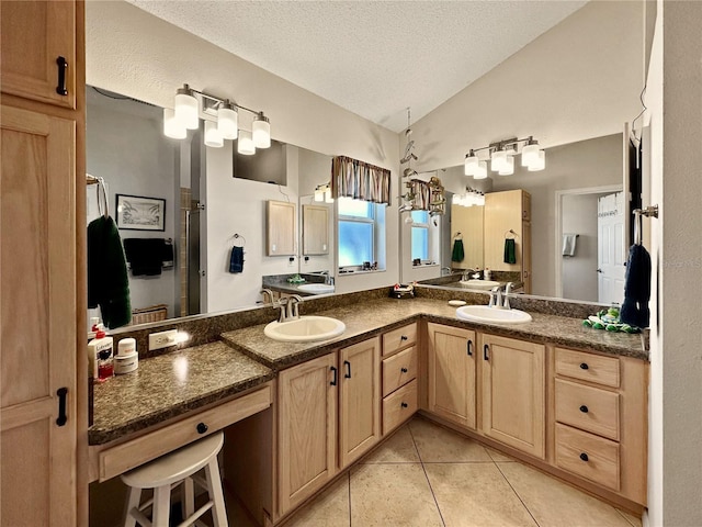 full bath featuring a textured ceiling, double vanity, tile patterned floors, lofted ceiling, and a sink