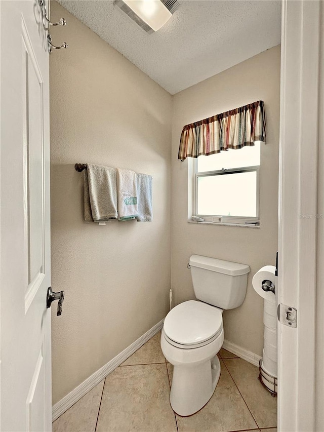 bathroom featuring tile patterned flooring, toilet, baseboards, a textured ceiling, and visible vents