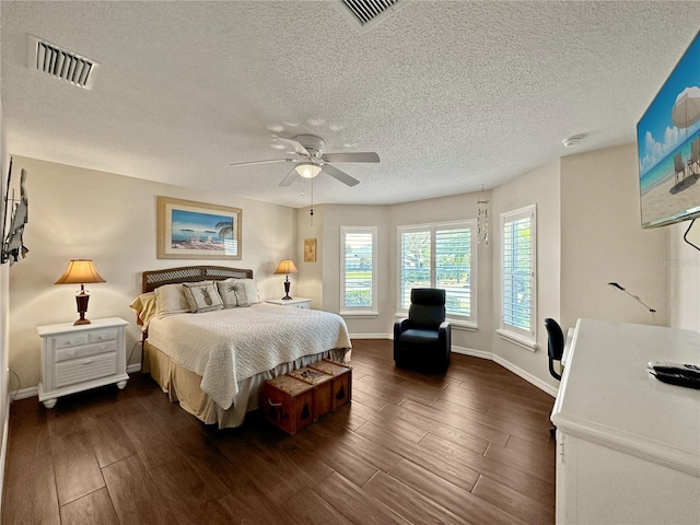 bedroom with dark wood-type flooring, baseboards, a textured ceiling, and visible vents