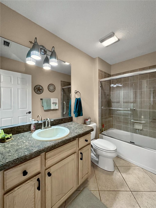 bathroom featuring combined bath / shower with glass door, tile patterned floors, toilet, vanity, and a textured ceiling