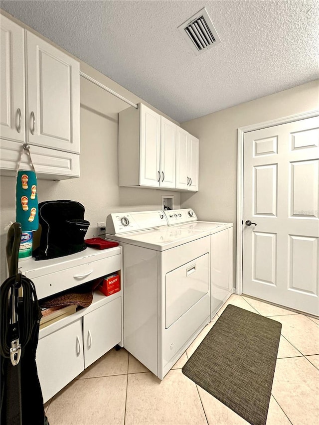 washroom featuring light tile patterned floors, cabinet space, separate washer and dryer, and visible vents