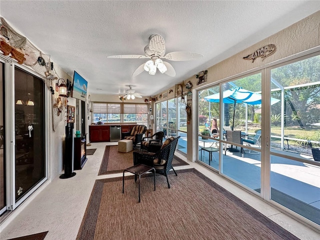 sunroom / solarium featuring plenty of natural light, a textured ceiling, a textured wall, and a ceiling fan