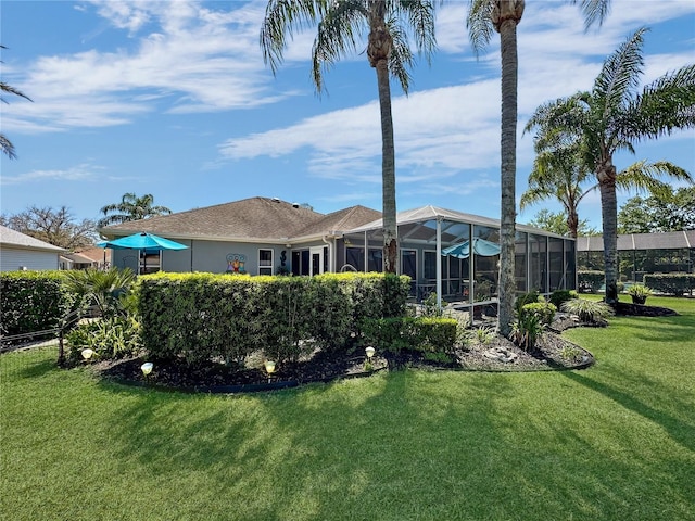 back of house featuring glass enclosure and a lawn
