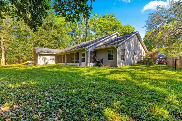 2922 SE 39th Pl, Ocala, FL 34480 - rear view of property featuring stucco siding, a sunroom, fence, and a yard