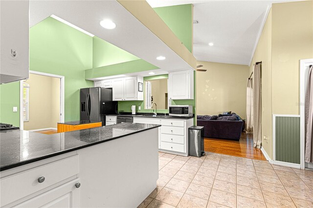 2922 SE 39th Pl, Ocala, FL 34480 - kitchen with black fridge, stainless steel microwave, dark countertops, white cabinets, and a peninsula