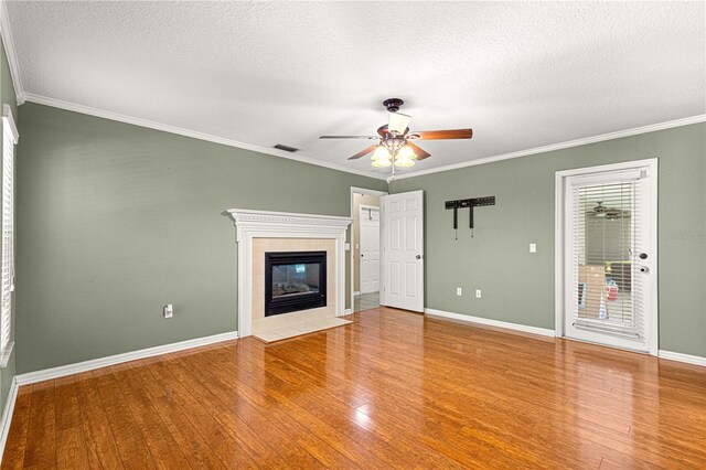2922 SE 39th Pl, Ocala, FL 34480 - unfurnished living room featuring crown molding, a tile fireplace, a ceiling fan, wood-type flooring, and visible vents