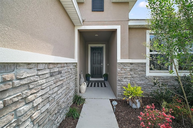 entrance to property featuring stucco siding and stone siding