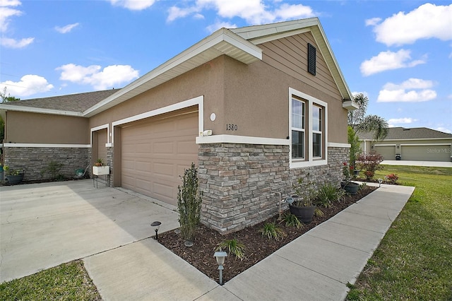 view of home's exterior featuring stone siding, an attached garage, concrete driveway, and stucco siding