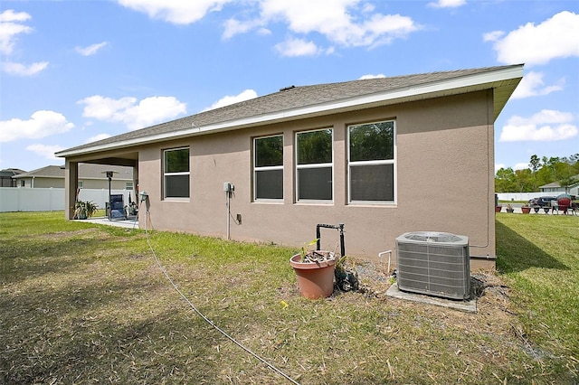 rear view of house featuring stucco siding, central AC unit, a yard, and a patio area