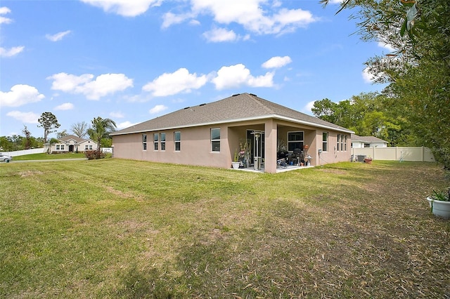 back of house with a lawn, stucco siding, fence, and a patio area