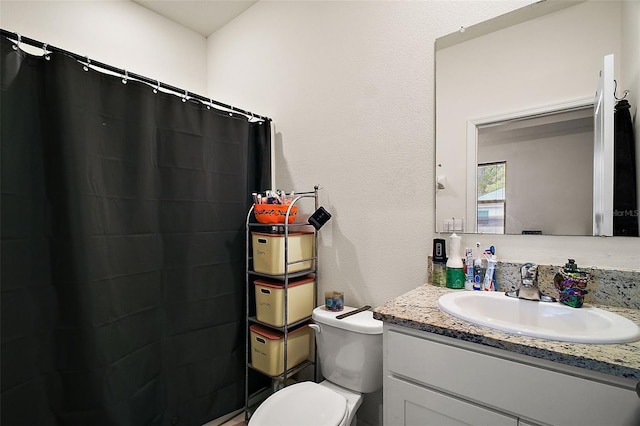 bathroom featuring a textured wall, toilet, a shower with shower curtain, and vanity