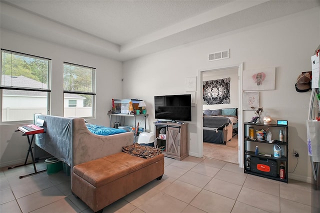 living area with light tile patterned flooring, baseboards, visible vents, and a textured ceiling