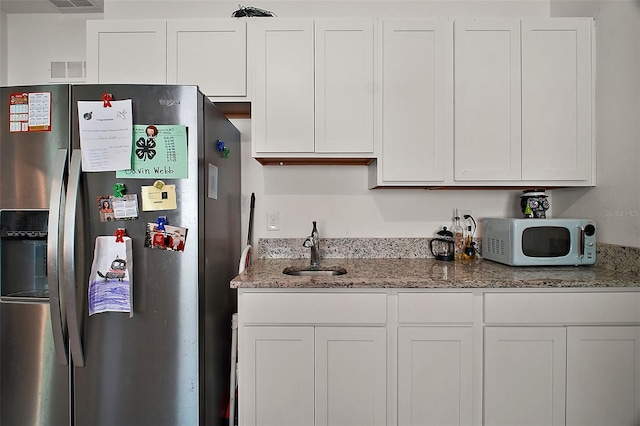 kitchen featuring white cabinets, a sink, stainless steel refrigerator with ice dispenser, and white microwave