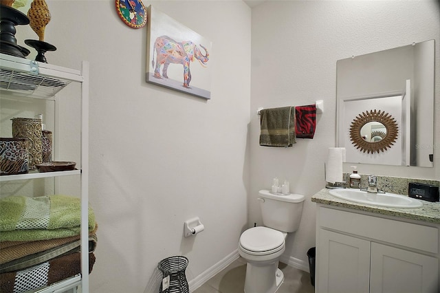 half bathroom with toilet, vanity, tile patterned floors, and baseboards