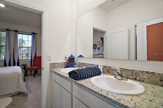 ensuite bathroom featuring double vanity, ensuite bath, and a sink