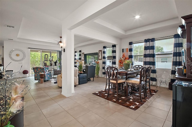 dining room with light tile patterned floors, a tray ceiling, a ceiling fan, and a wealth of natural light