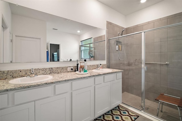 full bath featuring a stall shower, double vanity, and a sink