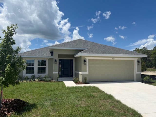 2166 NW 23rd Loop, Ocala, FL 34475 - view of front of house featuring stucco siding, an attached garage, a front yard, driveway, and roof with shingles