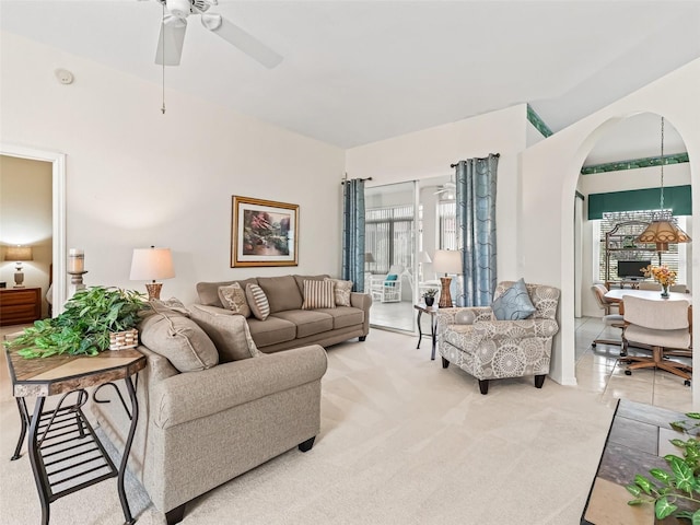 living room featuring light carpet, arched walkways, and a ceiling fan