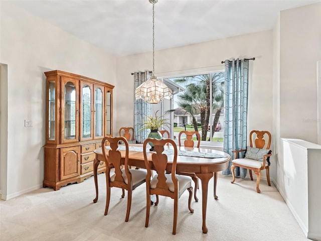 dining room with an inviting chandelier, baseboards, and light colored carpet