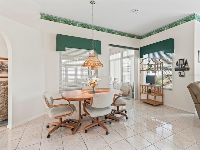 dining area with arched walkways, baseboards, and light tile patterned floors