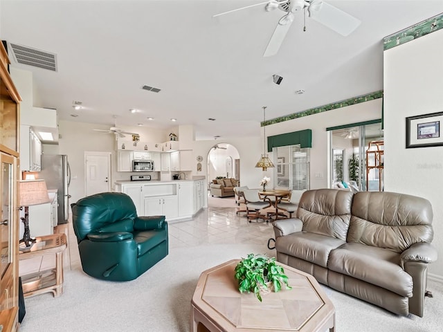 living area featuring arched walkways, light tile patterned flooring, visible vents, and a ceiling fan
