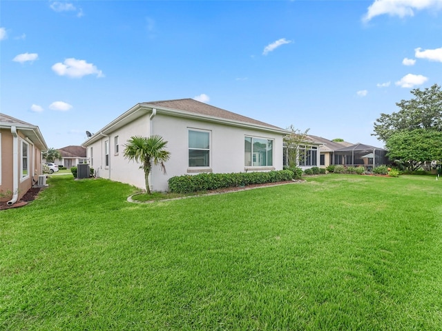 back of property with central air condition unit, stucco siding, and a yard