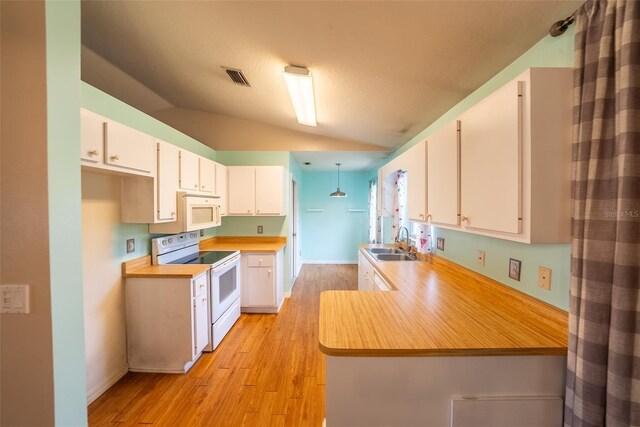 kitchen featuring light countertops, white cabinets, white appliances, a sink, and vaulted ceiling