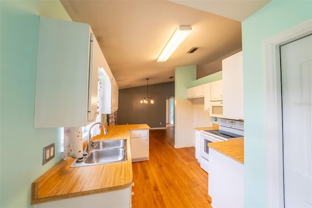 kitchen featuring visible vents, white appliances, a sink, light wood-type flooring, and vaulted ceiling