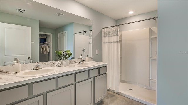 bathroom featuring a shower stall, double vanity, visible vents, and a sink