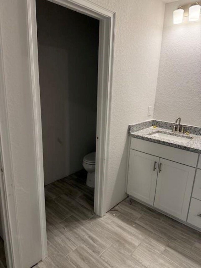 2218 NW 23rd Loop, Ocala, FL 34475 - bathroom featuring a textured wall, toilet, vanity, and wood finished floors