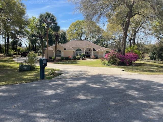 mediterranean / spanish house featuring stucco siding, curved driveway, and a front yard