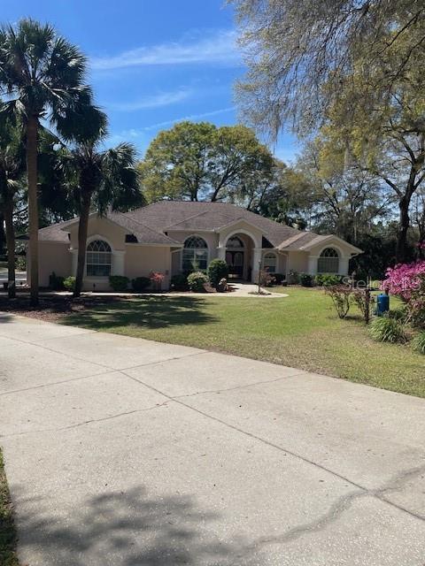 ranch-style home with stucco siding and a front lawn