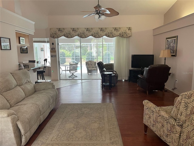 living room with baseboards, dark wood-style flooring, a high ceiling, and a ceiling fan