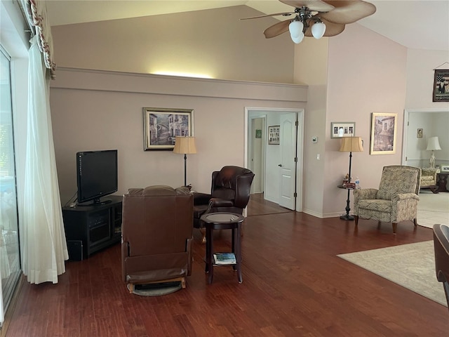 living area with a ceiling fan, high vaulted ceiling, baseboards, and wood finished floors