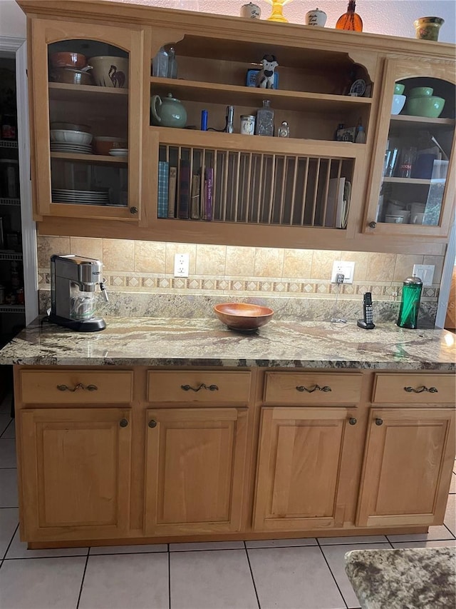 kitchen featuring glass insert cabinets, light stone countertops, and decorative backsplash