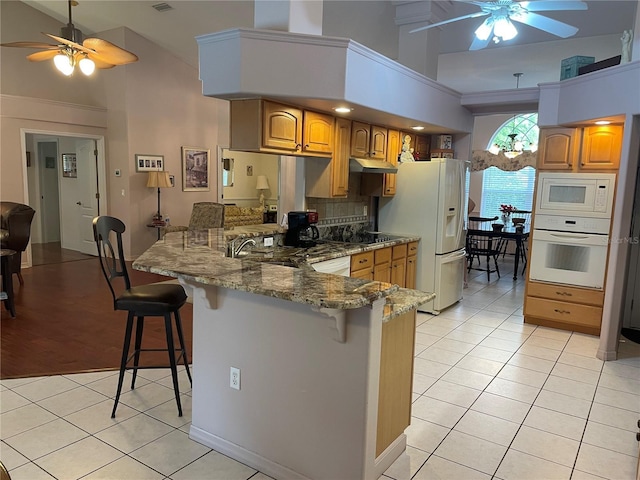 kitchen with light tile patterned floors, a peninsula, ceiling fan with notable chandelier, and white appliances