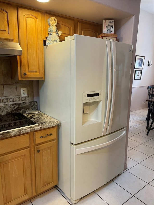 kitchen featuring black electric cooktop, light tile patterned floors, under cabinet range hood, backsplash, and white fridge with ice dispenser