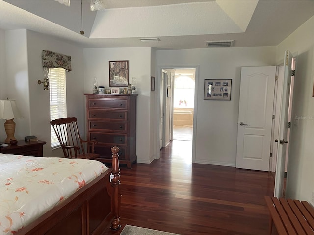 bedroom with baseboards, dark wood-style floors, visible vents, and a raised ceiling