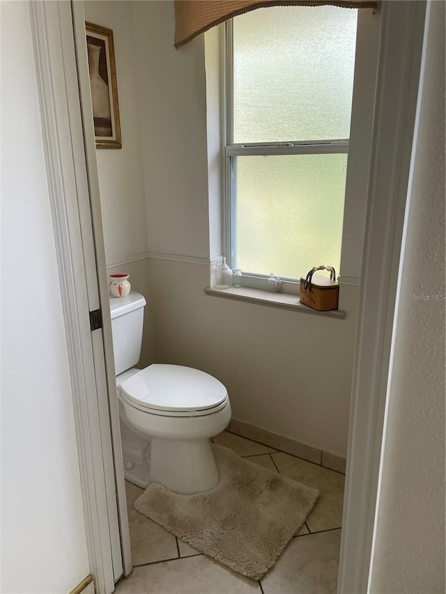 bathroom with baseboards, toilet, and tile patterned flooring