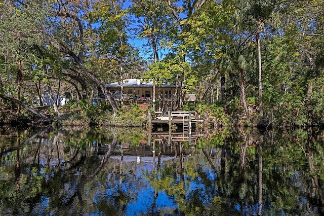 back of property with a water view, a view of trees, and stairway