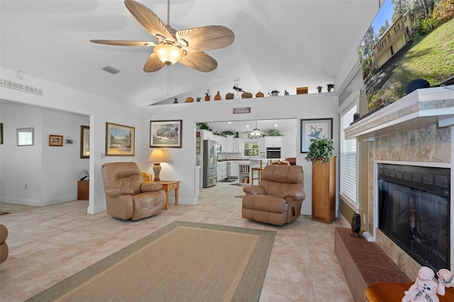 living area with vaulted ceiling, light tile patterned floors, visible vents, a tiled fireplace, and a ceiling fan