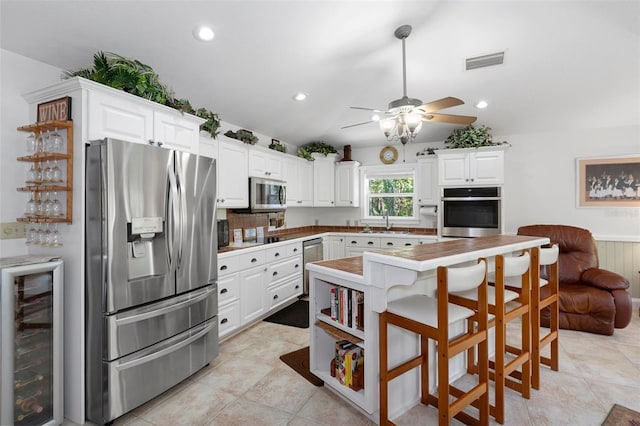 kitchen with wine cooler, wainscoting, stainless steel appliances, visible vents, and white cabinets