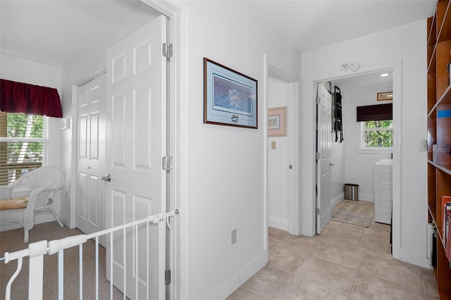 hall featuring light tile patterned floors, washer / clothes dryer, and baseboards